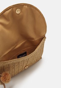 Borsa in paglia intrecciata di un beige chiaro con interiori in tessuto liscio. Presenta una chiusura a scatto dorata e un accento decorativo a pom-pom.