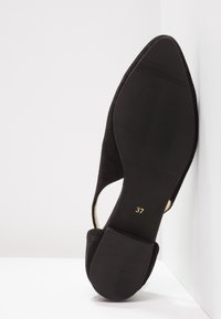 Schwarze Wildlederschuhe mit spitzem Zeh und Ausschnitten an den Seiten. Mit einer geriffelten schwarzen Sohle. Größe in Gold mit 37 markiert.