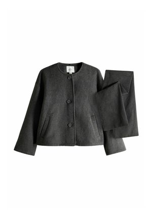 Veste en laine gris foncé boutonnée avec manches longues et pantalon assorti plié sur fond blanc.