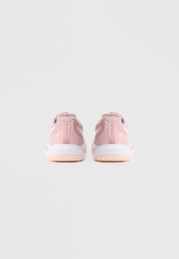 Ζευγάρι ροζ αθλητικών παπουτσιών με λευκές και ροδακινί σόλες, απεικονιζόμενο από πίσω σε απλό ανοιχτό γκρίζο φόντο.