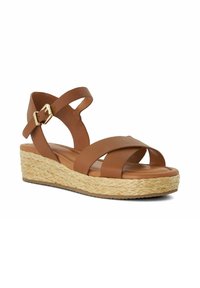 Brown wedge sandal with woven straw platform, two wide crisscross straps, ankle strap, and gold buckle closure on white background.