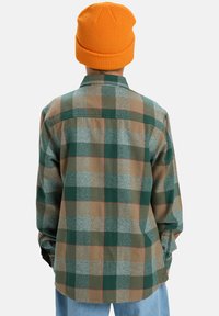 Gekleurde flanellen shirt in groene en bruine tinten, met een kraag, lange mouwen en knopenmanchetten, gecombineerd met een oranje gebreide muts.