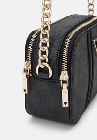 Bolso negro texturizado con cremalleras dobles, cadena de tono dorado y acentos de logo. Forma rectangular compacta con detalles de hardware suaves.