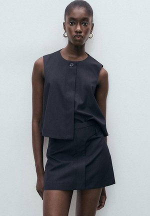 Sleeveless, dark striped top with a front button closure and matching fitted mini skirt, made from a smooth fabric with a subtle sheen.