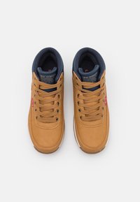 Par de zapatillas casuales de Levi Strauss en color beige con cordones marrones y cuellos acolchados en azul marino sobre fondo blanco.