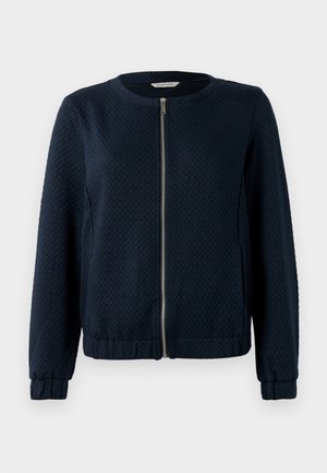 Marineblauwe ritsjack met een gestructureerd patroon, ronde halslijn en elastische manchetten. Gemaakt van geweven materiaal met een aansluitende pasvorm.