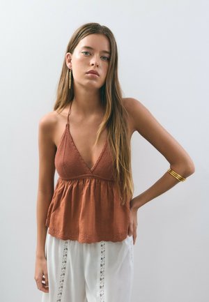Haut sans manches de couleur rouille avec un décolleté en V profond, un corps texturé et un ourlet fluide présentant des bords festonnés et des détails brodés.