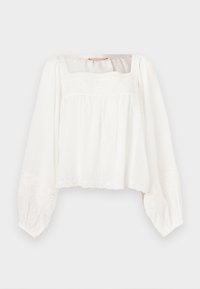 Blouse blanche à manches longues avec encolure carrée, coupe ample, et délicats détails floraux brodés sur la poitrine, les poignets et l'ourlet.