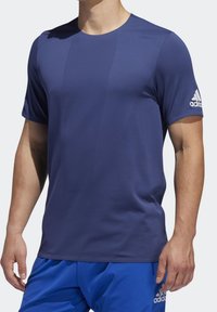 Námořnická modrá sportovní tričko s texturovanou, prodyšnou tkaninou, krátkými rukávy a logem Adidas na levém rukávu.