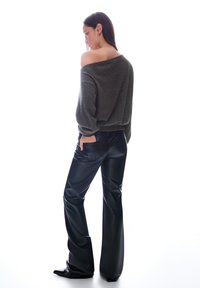 Temno zelena, off-shoulder pulover in črne, visoko pasne usnjene hlače. Obleka ima sproščen kroj in gladko teksturo.