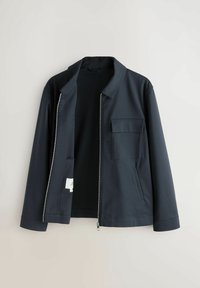 Veste marine avec fermeture éclair, col classique, deux poches avant et texture lisse. Le matériau semble léger et durable.