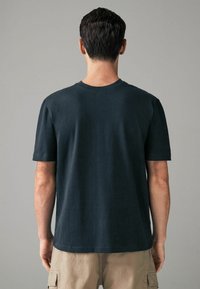 Zwart katoenen T-shirt met ronde halslijn, korte mouwen en een relaxte fit. De stof lijkt glad met minimale stikseldetails.
