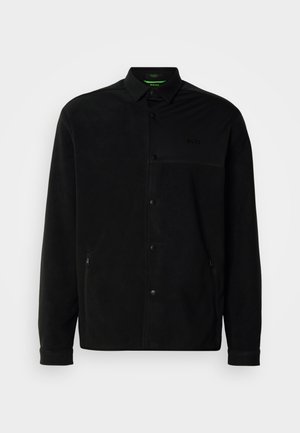 Μαύρο φλις μπουφάν με ποντες γιακά, κουμπιά με κούμπωμα, πλαϊνές τσέπες και διακριτική λεπτομέρεια logo στο στήθος. Ελαφρύ και υφητό ύφασμα.