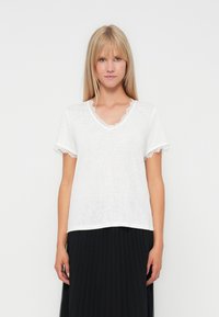 Hvid kortærmet t-shirt med v-hals og blondekant langs kanterne, lavet af et let, tekstureret stof.