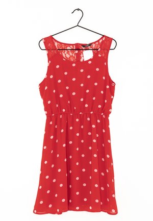 Rode mouwloze jurk met witte polkadots en kanten inzetstuk, met geplooide taille, hangend aan een zwarte hanger tegen een witte achtergrond.