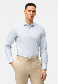 Hellblau gestreiftes Hemd mit Button-Down-Kragen, langen Ärmeln und Manschettenakzenten, kombiniert mit beigen Hosen, die einen Kordelzug haben.