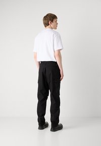 Svarte cargobukser med en avslappet passform, med sidelommer og elastisk midjebånd. Kombinert med en hvit t-skjorte med korte ermer.