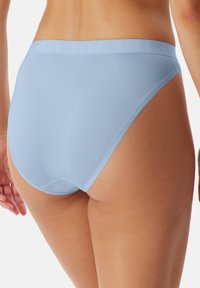Světle modré dámské brazilky s hladkou texturou a měkkým, elastickým páskem s decentním logem. Střih poskytuje plné pokrytí.