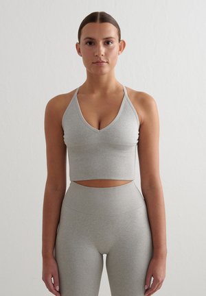Grijze geribbelde sportbeha met een diepe V-halslijn en verstelbare bandjes, gecombineerd met hooggeknipte grijze legging met een zachte stofstructuur.