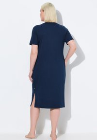 Abito di cotone blu navy con maniche corte, spacchi laterali e vestibilità comoda; texture liscia e design minimalista.