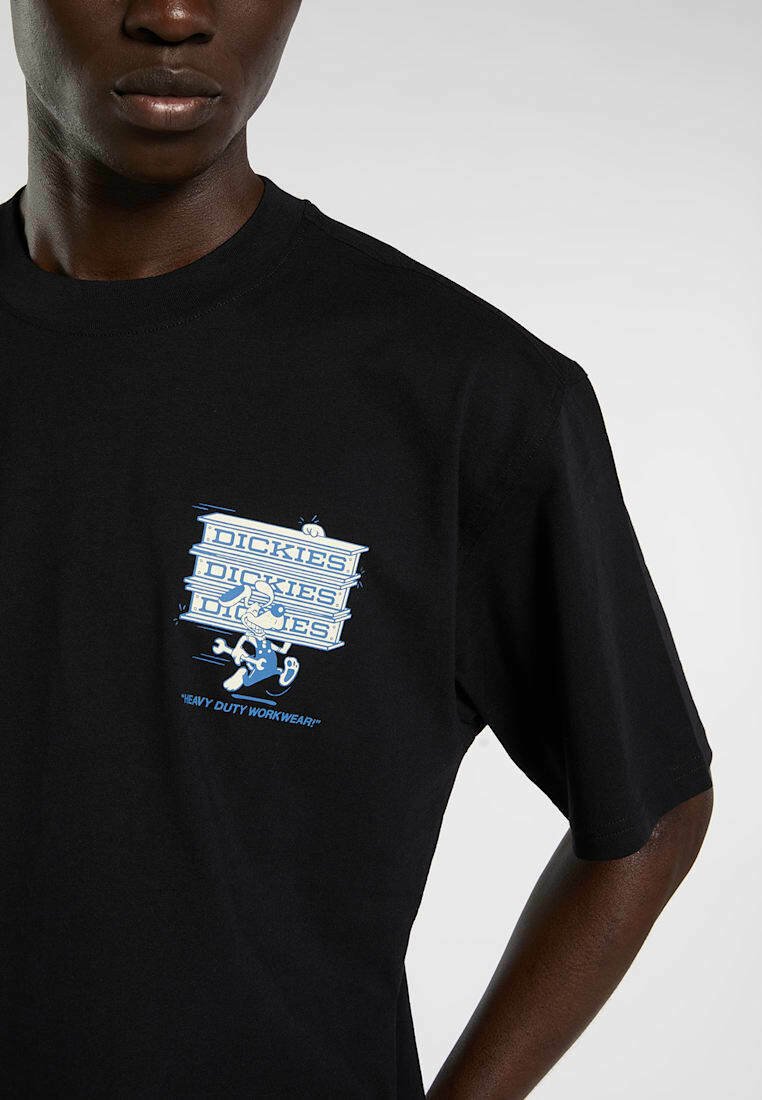 Person trägt ein schwarzes T-Shirt mit einer blau-weißen Cartoon-Grafik eines Kaninchens, das drei "Dickies" Kartons trägt, und dem Text "Heavy Duty Workwear".