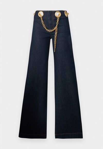 Mørkeblå jeans med vidde ben, store guldbeslag og et gyldent kædebælte, der er trækket gennem taljen.