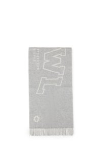 Jasnoszara wełniana chusta z białymi literami "W.T", małym logo krzyża i frędzlami, rozłożona na białym tle.