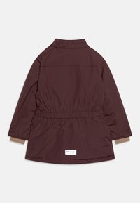 Burgundy let jakke med indsnævret talje, lange ærmer og en høj krave. Har beige manchetter og en lille hvid mærkeetiket ved kanten.