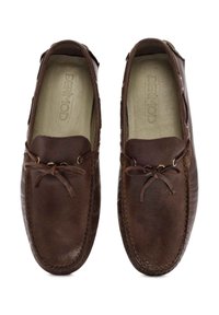 Zapatos de mocasín de cuero marrón con punta redondeada, cordones decorativos y sutiles detalles de costura en la parte superior. Acabado texturizado.