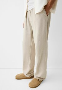 Beige linnen broeken met een relaxte pasvorm, met zijzakken en een rechte pijp. Gemaakt in combinatie met lichtbruin suède klompen.