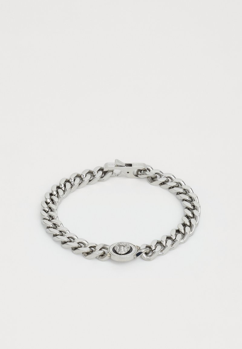 Metallkjedearmbånd med glanset sølvfinish, utstyrt med en oval lås med en sirkulær detalj i midten. Jevne ledd og polert overflate.