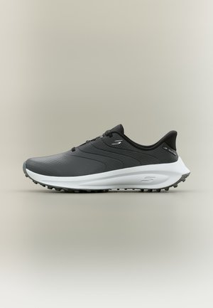 Zapatilla deportiva Skechers en negro y gris con suela blanca, diseño con cordones y suela de goma texturizada para mejor tracción.