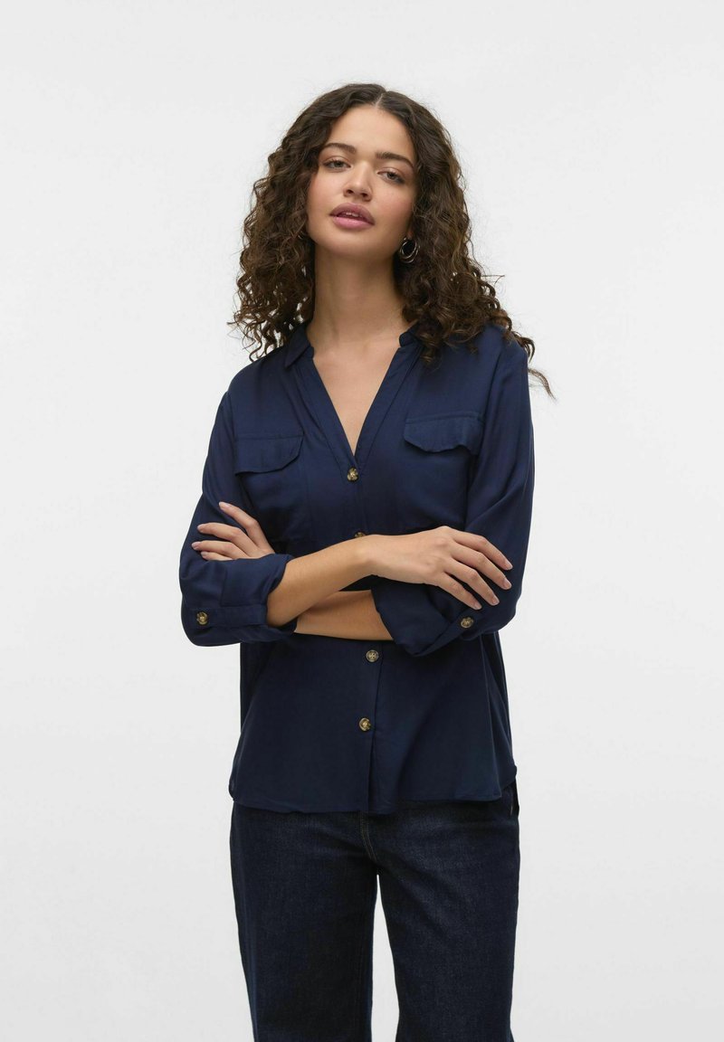 Camicia button-up blu navy con due tasche sul petto, maniche lunghe e bottoni dorati, caratterizzata da una vestibilità comoda e una texture liscia.
