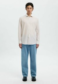 Pasi štrihanih gumbastih srajc v svetlih barvah s koničastim ovratnikom, v kombinaciji s svetlo modrimi širokimi jeans hlačami in črnimi čevlji. Preprost dizajn, sproščen fit.