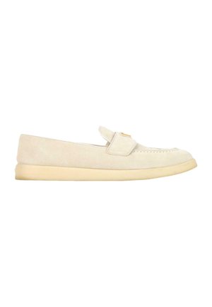 Beige ruskind loafer med flad sål og en remdetalje hen over toppen, vist fra siden på hvid baggrund.