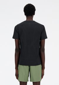 Black short-sleeve t-shirt with a textured back, featuring a subtle pattern; paired with light green shorts.