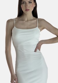 Abito midi bianco a coste con spalline sottili, silhouette aderente e dettaglio di arricciatura sottile in vita. Tessuto liscio e design minimal.