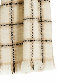 Écharpe en plaid tissée en crème, beige et noir. Tissu texturé avec des bords frangés et des motifs carrés prononcés. Tissage doux et épais.
