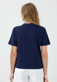 T-shirt di cotone blu navy con maniche corte e scollatura rotonda. Design semplice, texture liscia e vestibilità comoda.