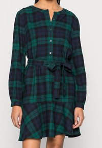 Robe à carreaux verts et bleu marine avec manches longues, boutonnée à l'avant et ceinture à la taille ; comprend une jupe évasée et un tissu texturé.