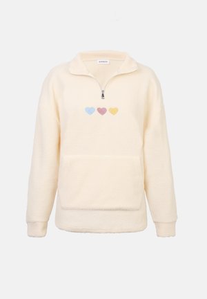 Sudadera de forro polar color crema con media cremallera en el cuello, con tres bordados de corazones en tonos pastel azul, rosa y amarillo en el pecho.