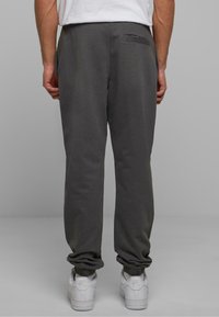 Grå sweatpants med en afslappet pasform, elastiske manchetter og detalje med lomme bagpå. Sammen med hvide sneakers. Glat tekstur.