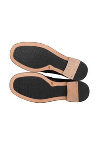 Suole nere di scarpe con fondo in gomma, dotate di una presa testurizzata e accenti in pelle color cuoio chiaro. Taglia contrassegnata come 37 sulla parte inferiore.