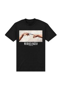 Dvě ruce se natahují k sobě, držící vzorovaný objekt, inspirovaný Michelangelovým Stvořením Adama, na černém tričku.