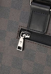Borsa in pelle con motivo a scacchi marrone, dotata di una cerniera nera e di accessori in argento, con dettaglio del logo sul tirante della cerniera.