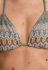 Triangelbikinitopp i flerfärgad spets med pastellgröna band, som har en strukturerad, mönstrad design av vågor och blommiga inslag.