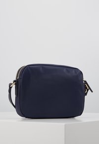 Borsa a tracolla blu navy realizzata in materiale liscio, forma rettangolare, zip e accessori in tonalità dorata, tracolla nera regolabile.