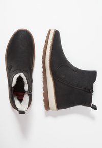 Svarta läderankelstövlar med en texturerad yta, sidodragkedja, vit sula och plyschfoder, med en tan gummiyttersula.