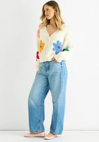 Cream knit cardigan with colorful flower embroidery, paired with light blue wide-leg jeans and light pink flats.