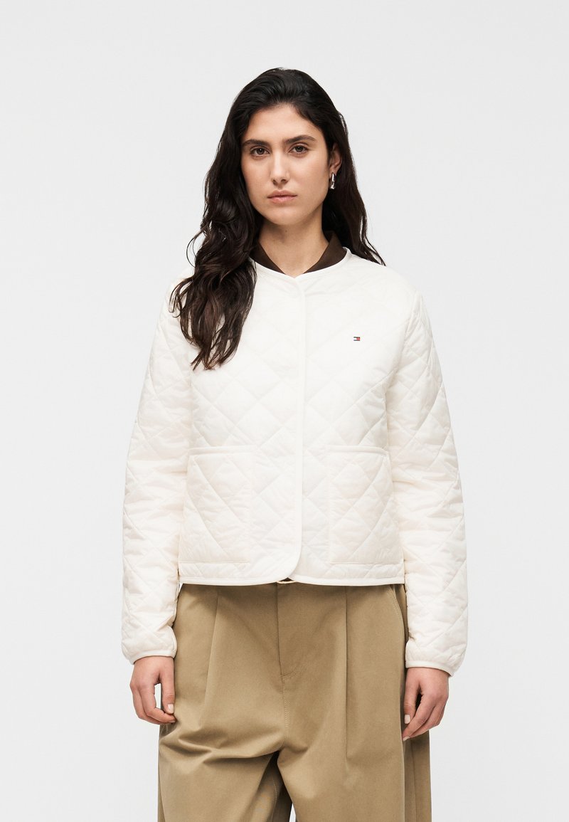 Λευκό μπουφάν με κεντητό σχέδιο, στρογγυλή λαιμόκοψη, κλείσιμο με κουμπιά στο μπροστινό μέρος και πλαϊνές τσέπες. Συνδυάζεται με καφέ παντελόνια, με υφή φυσικού υφάσματος.